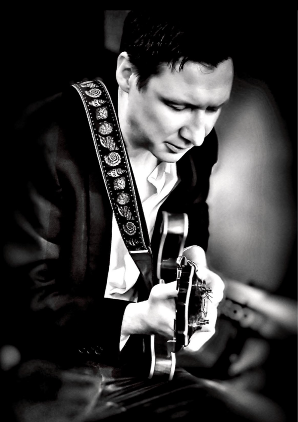 Black and white portrait of Jamie Glew side on playing an electric guitar
