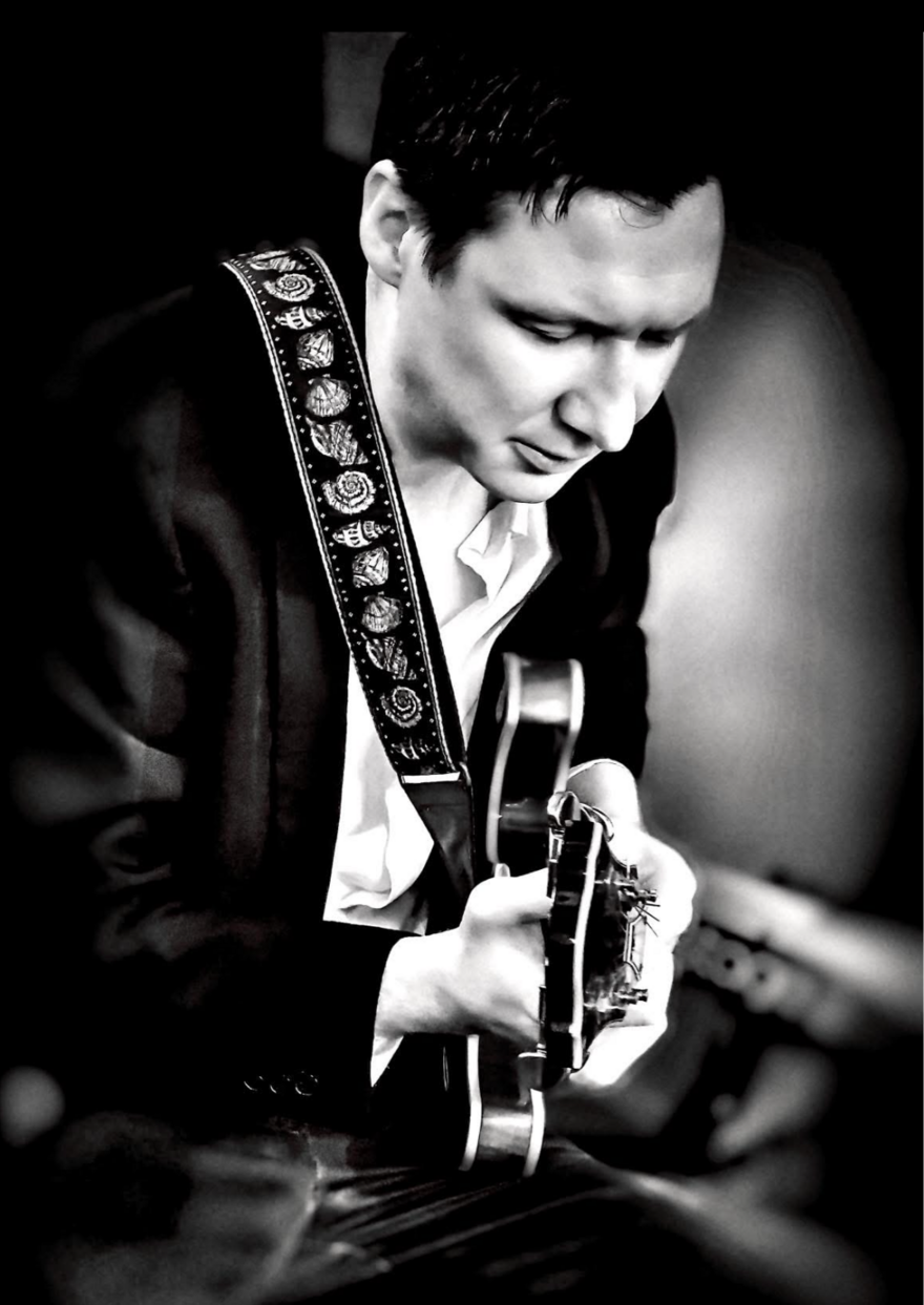 Black and white portrait of Jamie Glew side on playing an electric guitar